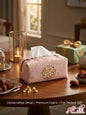 Handcrafted dusty rose tissue box cover with gold Arabic calligraphy embroidery on a wooden table