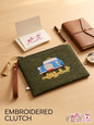 Hand-embroidered green clutch featuring a classic blue Beirut service taxi and Arabic calligraphy